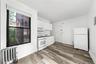 Kitchen with white appliances, radiator, white cabinetry, wood finished floors, and backsplash