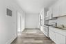 Kitchen with white appliances, electric panel, tasteful backsplash, light wood-type flooring, and white cabinets