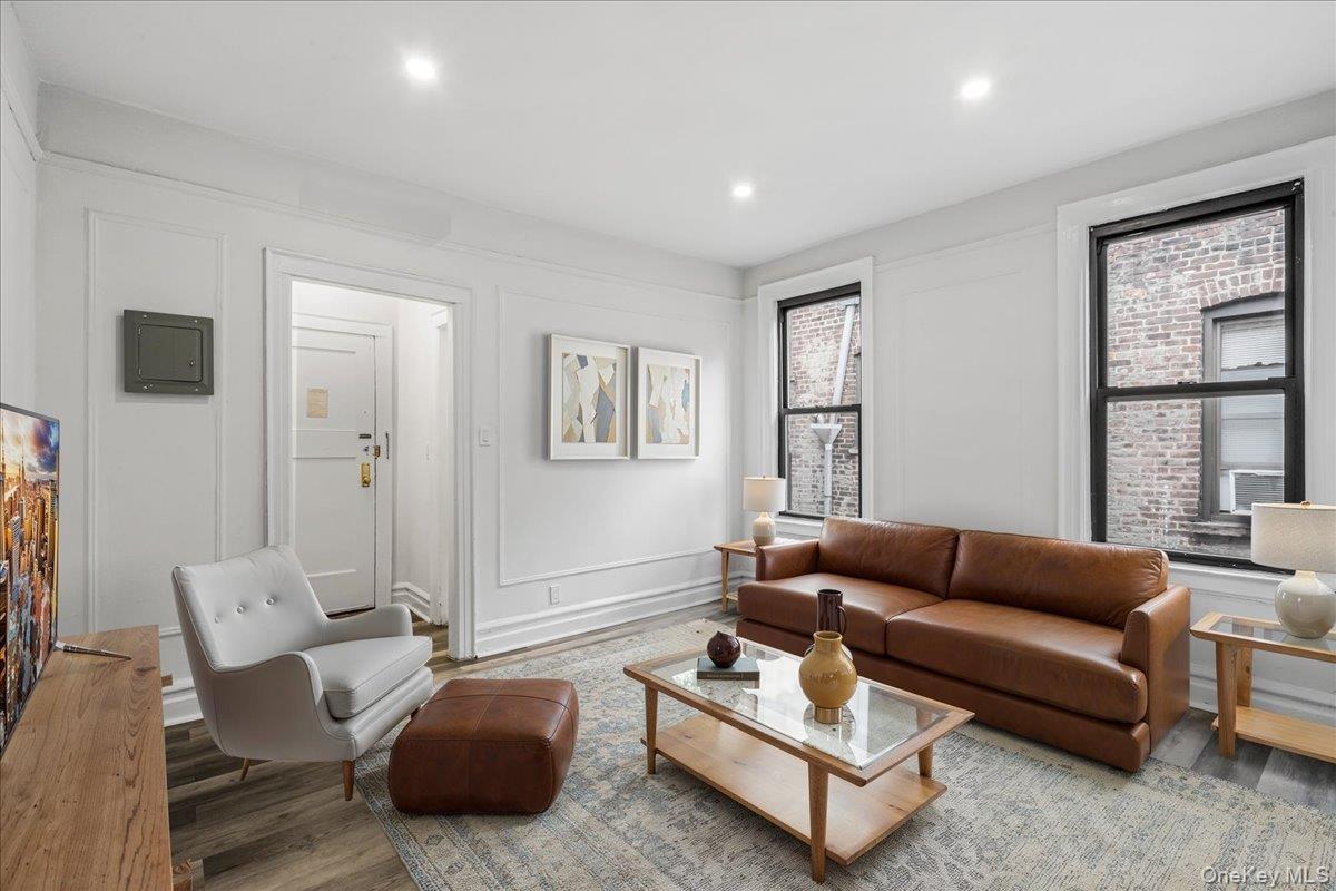 Living room with a decorative wall, wood finished floors, electric panel, and recessed lighting