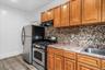 Kitchen with stainless steel gas stove, wood finished floors, under cabinet range hood, and brown cabinetry