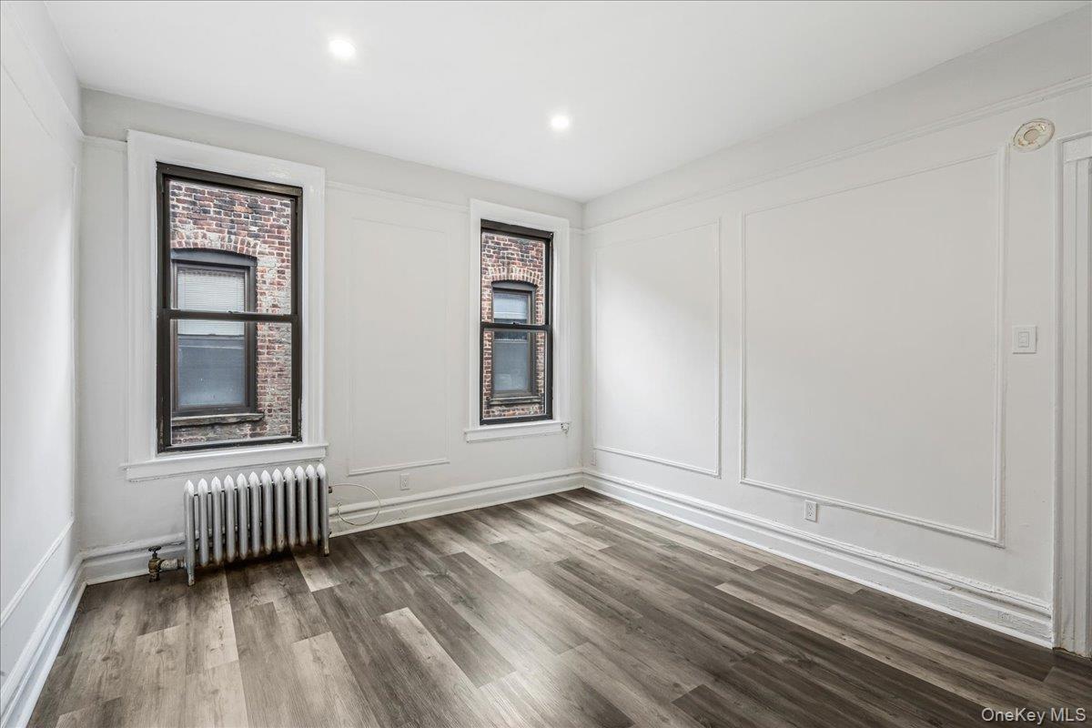 Spare room with radiator, wood finished floors, recessed lighting, and a decorative wall