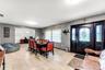 Spacious room featuring neutral tile flooring, a multi-blade ceiling fan, and large windows