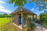 Expansive open-air lot featuring a grassy lawn, metal fencing, and perimeter hedging