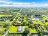 Aerial perspective of a sprawling property featuring expansive landscaped grounds, mature palm trees, a dedicated swimming pool, and an attached multi
