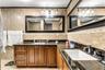 Bathroom featuring floor-to-ceiling stone-finish tile, glass-enclosed shower with a multi-function showerhead, dark stone-finish vanity countertop, an