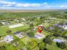 Aerial perspective featuring a sprawling parcel with expansive green space, a paved driveway, and an in-ground swimming pool