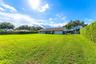 Expansive backyard featuring a large grass lawn, mature trees, and privacy-providing perimeter hedges