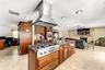 Spacious interior featuring neutral wall tones, large-format tile flooring, a multi-blade ceiling fan, and expansive windows with dark-finish frames