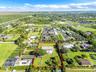 Aerial perspective of a sprawling property featuring a multi-pitched roof residence, a rectangular swimming pool, extensive manicured grounds, mature 