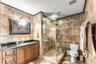 Room featuring large-format neutral tile flooring, a central ceiling fan with integrated light fixture, and horizontal window blinds