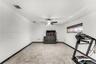 Room featuring large-format stone-style tile flooring, dark wood-finish interior doors, and a ceiling fan with integrated lighting