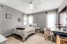Neutral-toned interior featuring large-format tile flooring, dual-window exposure, a ceiling-mounted light fixture with fan, and bifold closet doors w