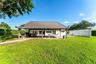 Expansive backyard featuring a manicured lawn, perimeter privacy hedging, and mature palm trees