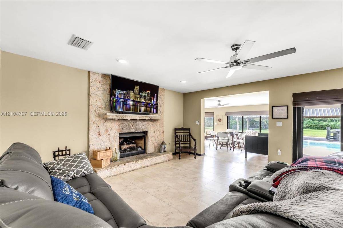 Living area featuring floor-to-ceiling stone fireplace, raised hearth, mantel, recessed lighting, and ceiling fan