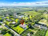 Aerial perspective of a sprawling lot featuring a rectangular swimming pool, concrete patio, extensive lawn, and mature perimeter landscaping