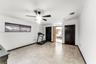Room featuring large-format stone-style tile flooring, dark wood-finish interior doors, and a ceiling fan with integrated lighting