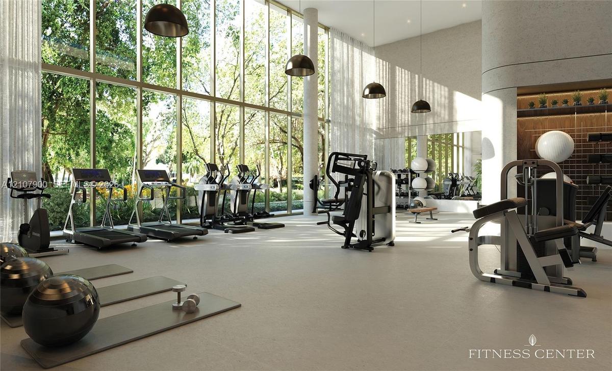 Fitness center featuring floor-to-ceiling windows, high ceilings, structural columns, and recessed pendant lighting