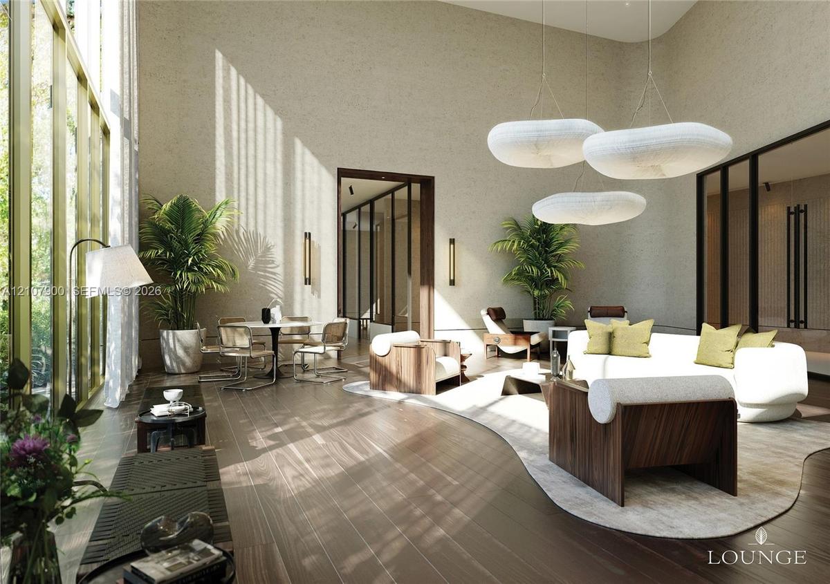 Expansive interior space featuring double-height ceilings, floor-to-ceiling windows with brass-tone frames, textured wall finishes, wide-plank wood-fi