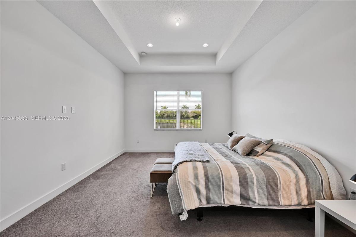 Neutral-toned wall-to-wall carpeting, recessed ceiling lighting, and a glass-paned sliding door providing exterior access