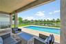Covered concrete patio featuring tiled flooring, built-in recessed lighting, an in-ground swimming pool, and metal perimeter fencing