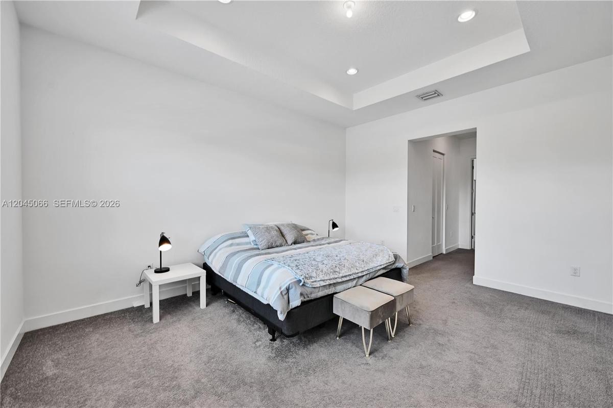 Tray ceiling featuring recessed lighting, wall-to-wall carpeting, and a multi-pane window