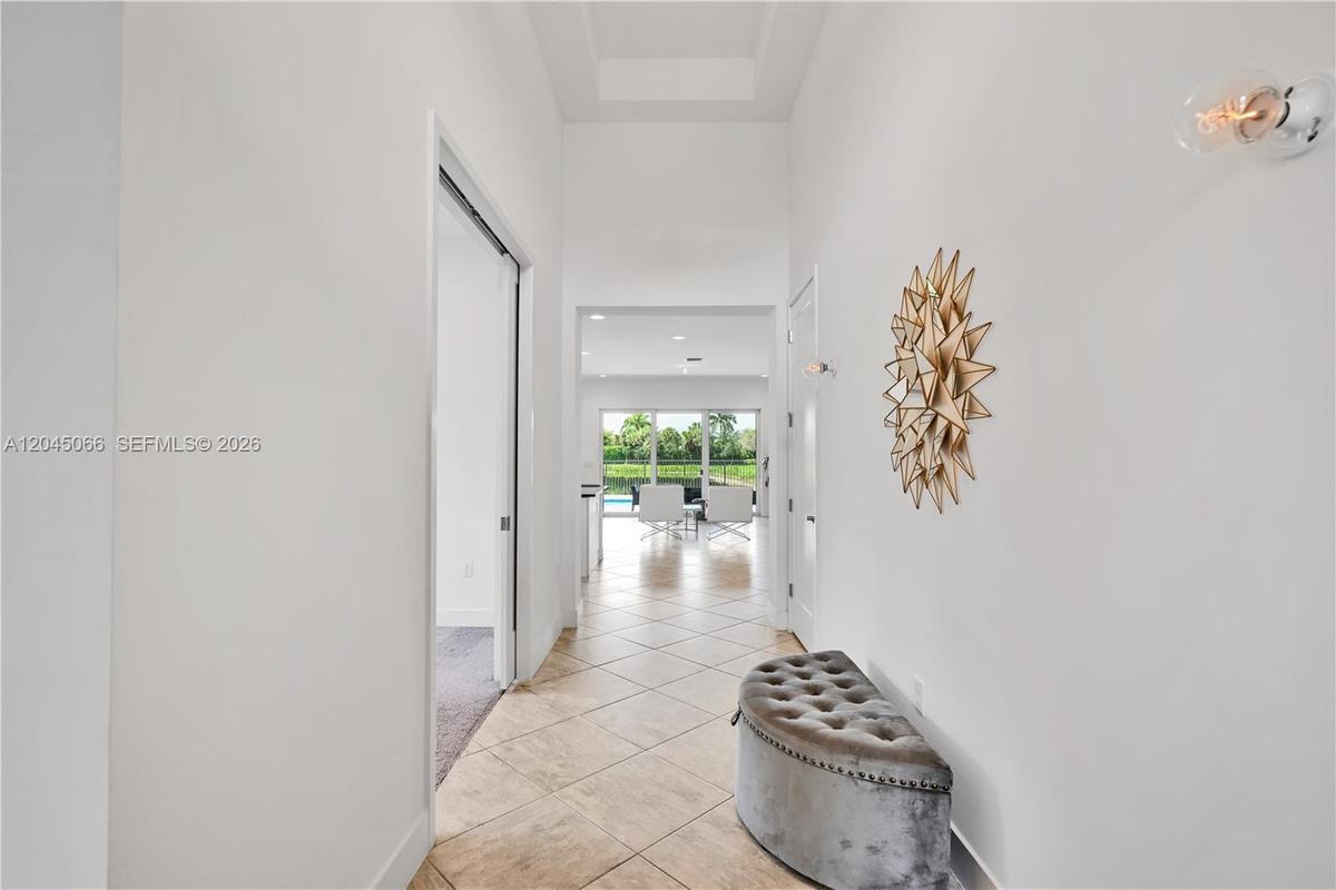 Tray ceiling with recessed lighting and neutral carpeting throughout