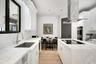 Kitchen featuring white cabinetry, stone countertops, stainless steel undermount sink, built-in double wall oven, and wood-finish flooring