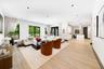 Open-concept interior featuring wood-finish flooring, recessed lighting, expansive windows with black frames, and a kitchen island with a stone-finish