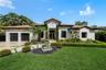 Single-story residence featuring a tile roof, stucco exterior, two-car garage, stone water fountain, and manicured landscaping
