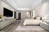 Tray ceiling with recessed lighting, integrated floor-to-ceiling cabinetry, wood-finish flooring, and minimalist flat-panel doors
