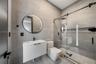 Room featuring wood-finish flooring, wall-mounted ductless air conditioning unit, tall vertical window, and high-contrast dark door casing
