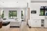 Open-concept interior featuring light wood-finish flooring, white shaker-style cabinetry, solid-surface countertops with stone-pattern veining, and mu
