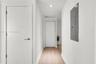 Hallway featuring light wood-finish flooring, white panel doors, recessed ceiling lighting, and a bifold closet door