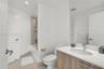 Vanity featuring a light wood-finish cabinet, white countertop with an integrated oval sink, and a full-width mirror