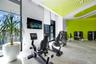 Fitness facility featuring floor-to-ceiling windows, high ceilings with decorative acoustic panels, polished concrete flooring, and wall-mounted telev