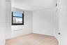 Light-filled interior featuring wood-finish flooring, a large window with urban skyline exposure, and clean, neutral wall finishes