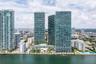 High-rise complex featuring glass-facade towers, an elevated outdoor pool, landscaped podium deck, and direct waterfront placement