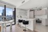 Kitchen featuring a quartz-topped island, light wood-finish cabinetry, built-in stainless steel oven, floor-to-ceiling windows, and floating shelving