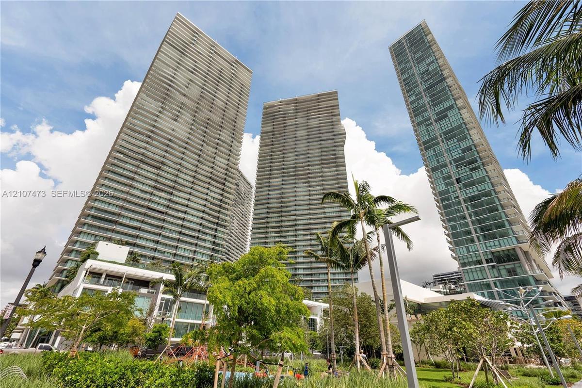 High-rise residential towers featuring glass-paneled facades, private balconies, and integrated landscaping with mature palm trees