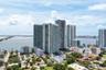 High-rise glass and concrete residential towers situated on a waterfront peninsula featuring multi-level podium parking structures, rooftop recreation