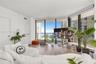 Floor-to-ceiling windows, wood-finish flooring, and an attached balcony with metal railing