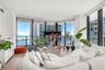 Floor-to-ceiling windows, wood-finish flooring, and black metal-framed balcony access with a glass railing