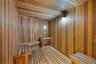 Sauna featuring wood-plank wall paneling, slatted wood-finish flooring, tiered built-in wood bench seating, and integrated wall lighting