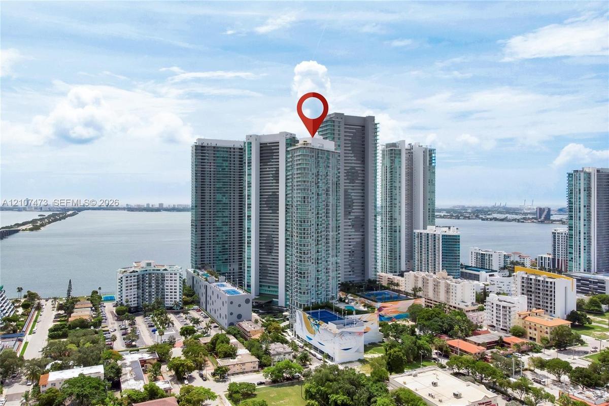 High-rise residential tower featuring a glass facade, expansive water proximity, and a multi-level structure with prominent podium parking and podium-