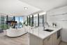 Kitchen featuring a white quartz countertop, undermount sink, gooseneck faucet, light-finish cabinetry, and built-in microwave, complemented by wood-f