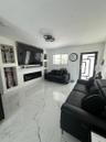 Large-format porcelain tile flooring, built-in wall niches, linear electric fireplace, modern flush-mount multi-ring ceiling lighting, and geometric-p