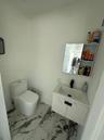 Floating vanity with stone-patterned cabinetry, rectangular sink, matte black faucet, and large-format porcelain tile flooring