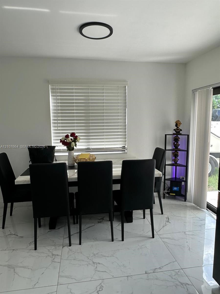 Large-format stone-finish tile flooring, recessed circular ceiling lighting, and vertical window blinds
