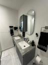 Floating double vanity featuring a grey stone-finish countertop, dual rectangular undermount sinks, vertical-slat cabinet doors, dual oval wall-mounte