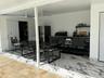 Covered outdoor kitchen area featuring high-contrast tile flooring, matte black cabinetry, a built-in grill, and an integrated ceiling fan